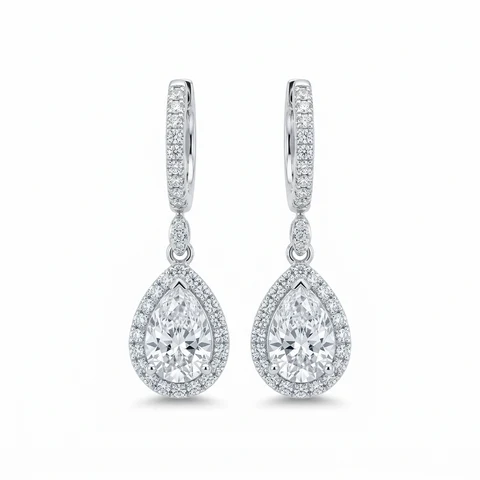 A complete pair of white-gold diamond huggie earrings on white.